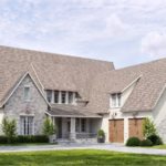 A two-story house with light brick and siding exterior, steep gable roofs, double garage doors, and landscaped front yard with trees and shrubs.